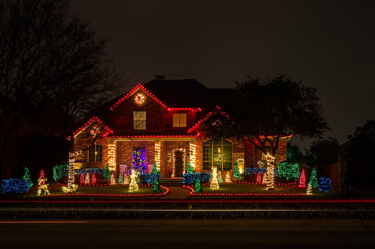 A private residence lit up with Christmas lights across the roofline and front yard