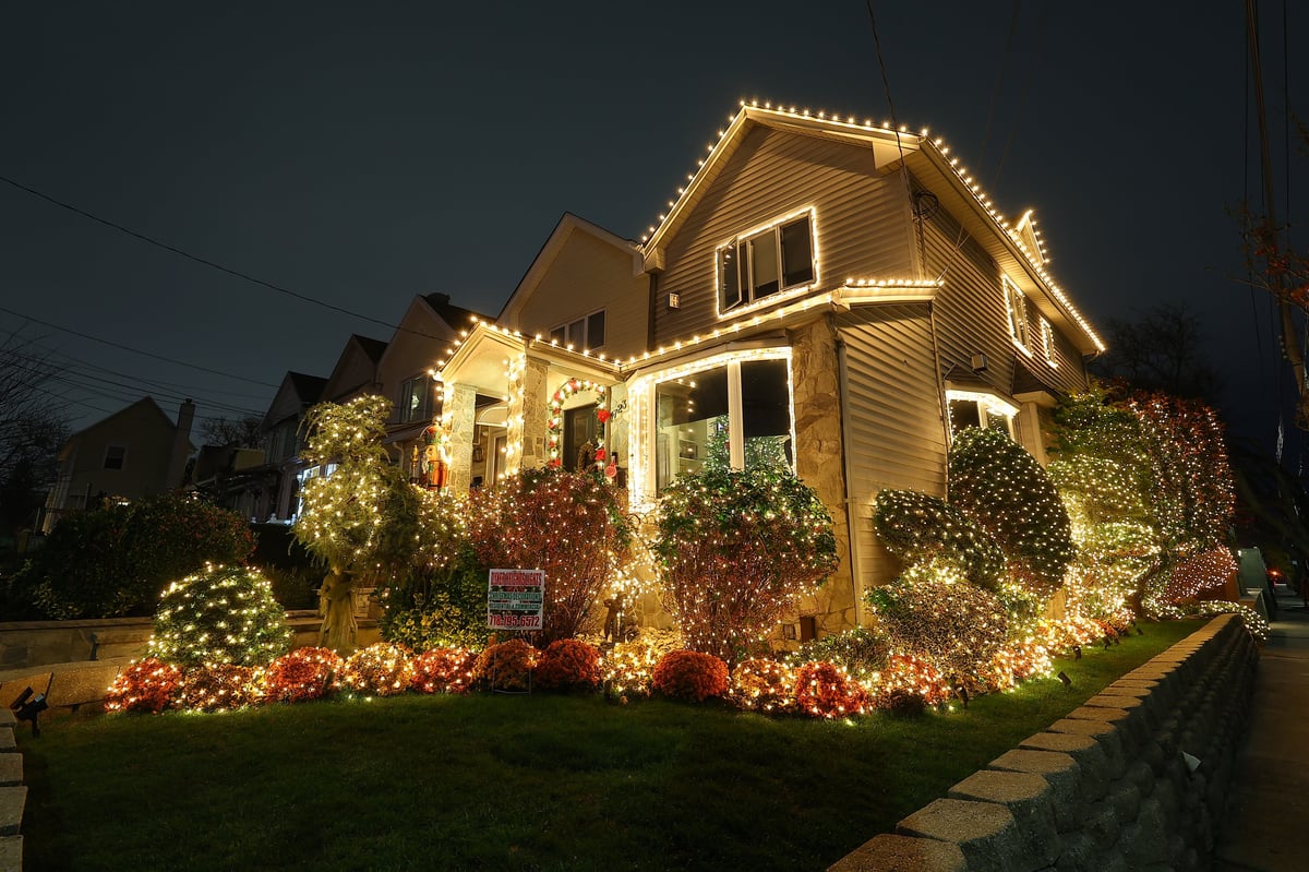 An elaborately decorated home lit with holiday lights across the facade