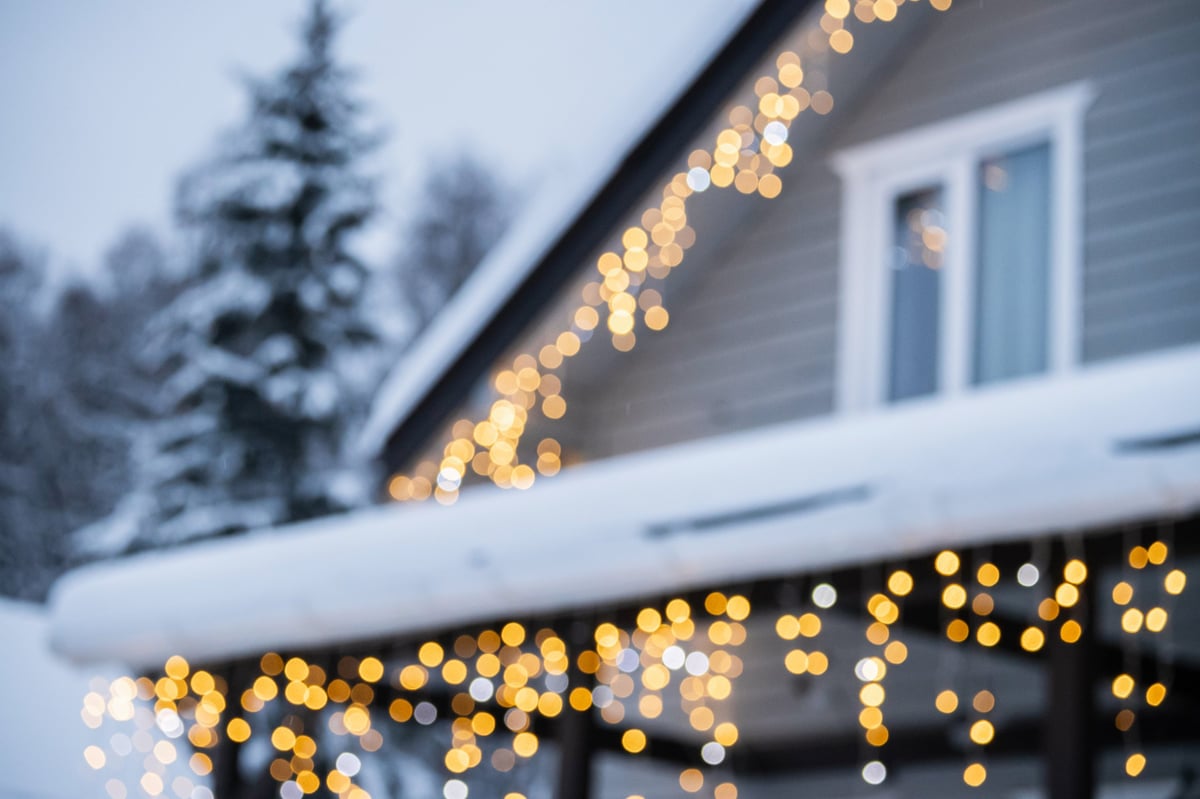 A house glowing with warm festive lights on a snowy winter evening