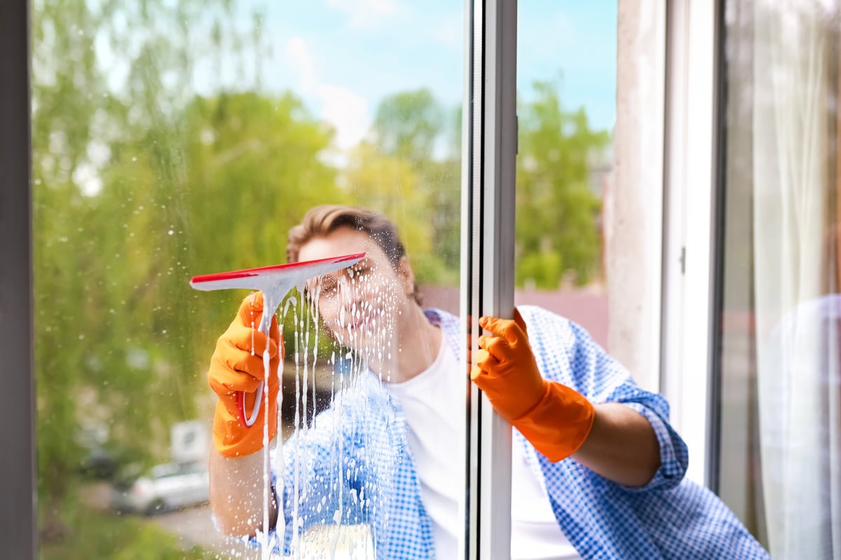 Window cleaner washing exterior glass with a squeegee and soapy water